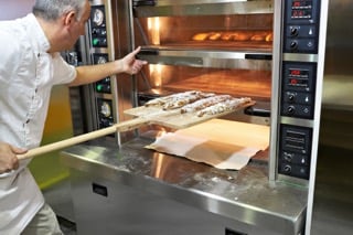 Baker bakes bread in oven